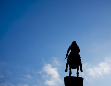 Silhouette of a rider on a horse on blue sky background. legs in stirrups, dagger in hand. Leopold's Fountain in Innsbruck, Austria