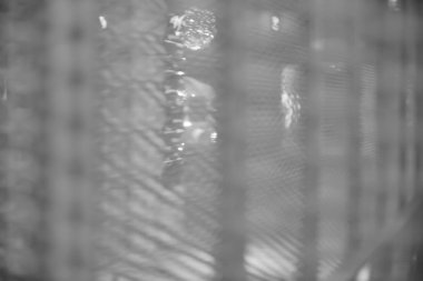 Arka plan olarak bulanık, bulanık, beyaz metalik ağ örülmüş, bulanık bir örümcek ağı var. beyaz ve siyah. 