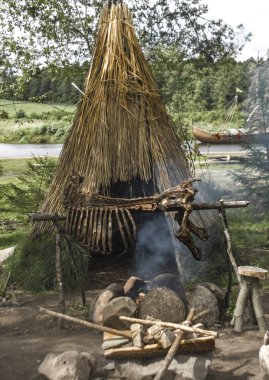 Barakanın önünde yanıyor Taş Devri gıda pişirme.