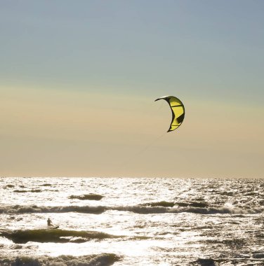 Rüzgâr Sörfçüsü Panorama 'sı, Surfing.Strong Rüzgârları bu Rüzgar Sörfçüsüne yardım ediyor. Suda eğlenen ve uçurtmayla sörf yapan bir adamın silüeti. Güçlü rüzgarlarla dalgaları tutuyor.. 
