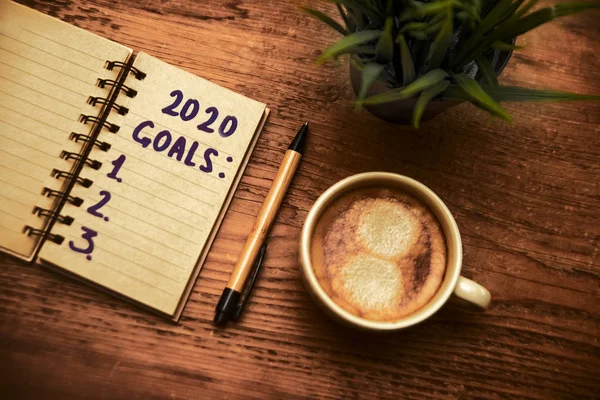 木製のテーブルでコーヒーを飲みながら ノート 3つのステッチアイテム 2020年の新年度目標 — ストック写真