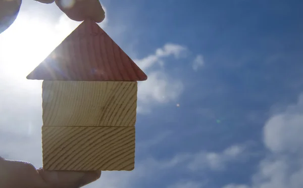 晴れた空と太陽光線に対して木造住宅グッズを持っている手 — ストック写真
