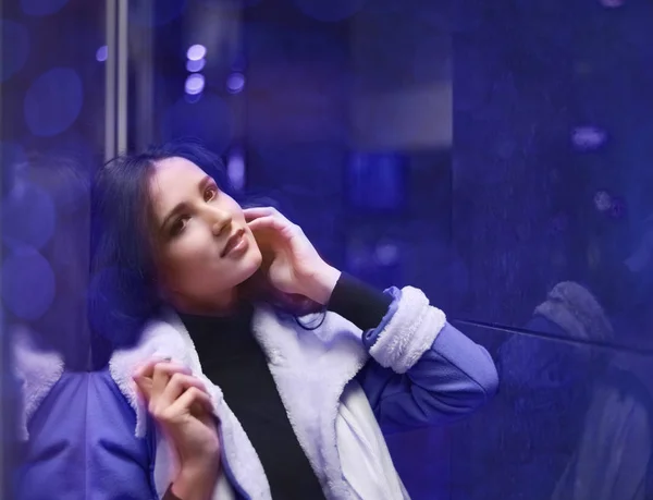 portrait of  young adult woman stand near big shop window. Night scene.