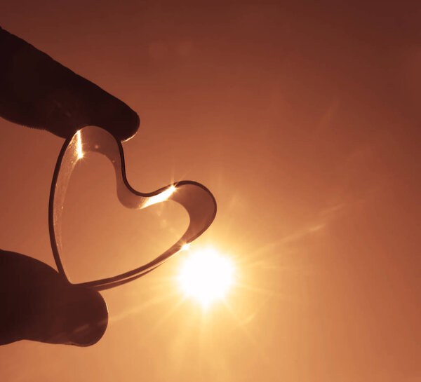 silhouette of one Heart Shape in the Hand on sunrise Sky
. 