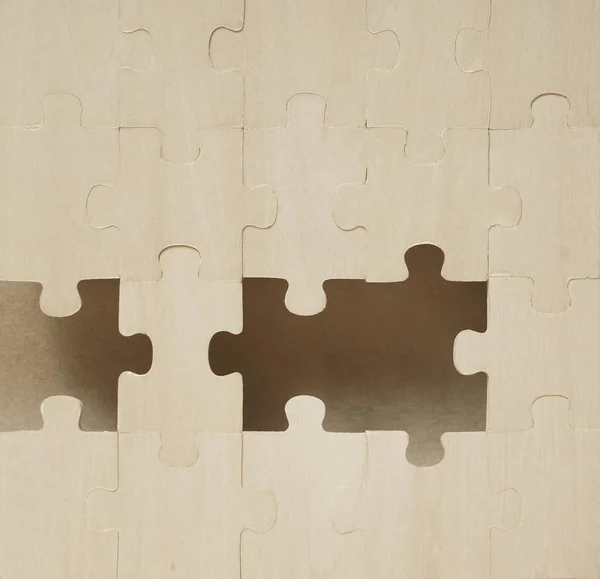 Placing missing pieces of wooden puzzle. business concept. craft brown paper  background.