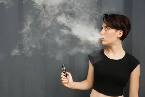Mladá dívka kouří elektronickou cigaretu. ženský model vaping a va — Stock fotografie