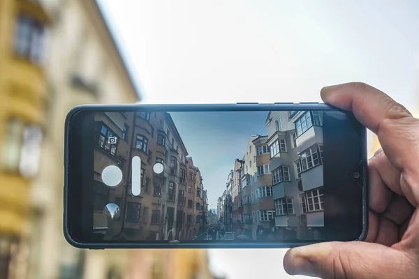 screen of mobile phone in male hand and winter Austria view (my photo)  on Innsbruck town background.