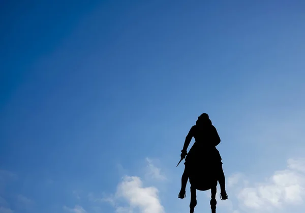 青い空の背景に馬に乗っているライダーのシルエット 脚を振動させ短剣を手にオーストリアのインスブルックにあるレオポルドの泉 — ストック写真