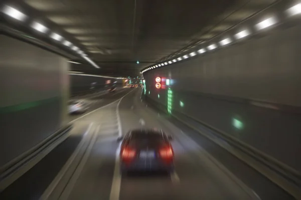 blurred image of  tunnel  with lights, defocused cars and speed limit signs. Signs in dark tunnel by tilt-shift speed limit and motion