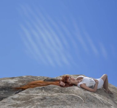 Güzel kızıl saçlı genç bir kadın taşların üzerinde yatıyordu. Beyaz kısa, seksi bir elbise ve kapalı gözleri vardı. Çok seksi bir kız. Güzellik modası. Dişi dağın arka planında rahatlamış.