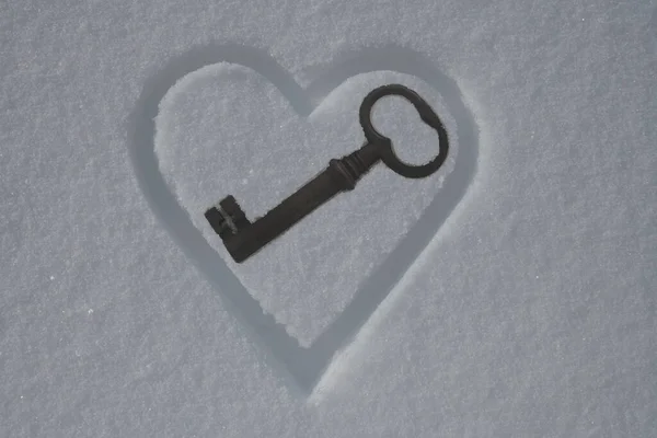 Heart symbol on  snow, love and Happy St. Valentine\'s day. old rusty key  inside heart.