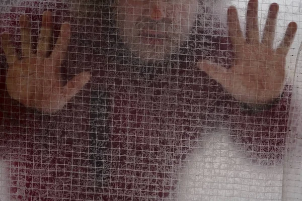 a man behind a transparent film covered with hoarfrost. wintertime serason