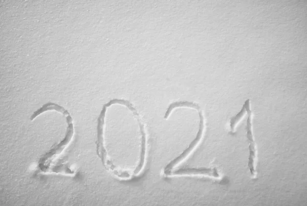 top view. Numbers, calendar date, inscription 2021 on natural snowy surface in wintertime. Text, Winter New Year holiday background. 2021 happy new year. snow texture