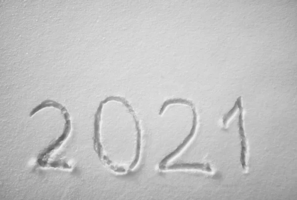 top view. Numbers, calendar date, inscription 2021 on natural snowy surface in wintertime. Text, Winter New Year holiday background. 2021 happy new year. snow texture