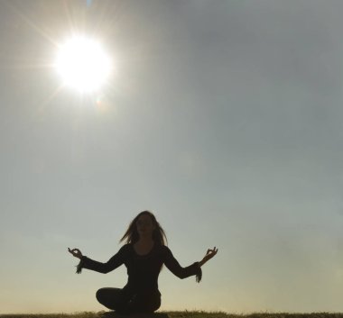 Bahar Yogası yapan güzel genç bir kadının silueti. güneşli bir gün.
