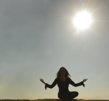 Bahar Yogası yapan güzel genç bir kadının silueti. güneşli bir gün.