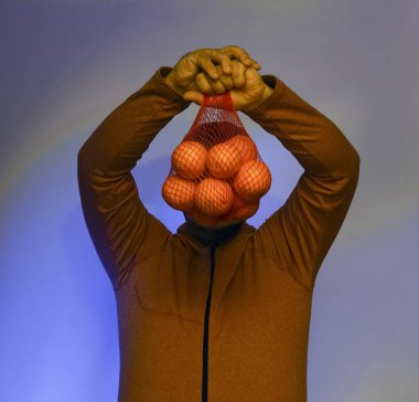 Ağın içinde portakal tutan bir adam.