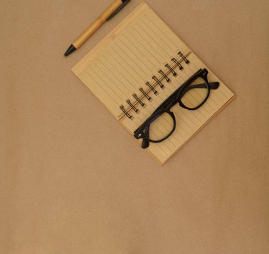 Açık defter, kalem ve gözlüklü üst görünüm masası 
