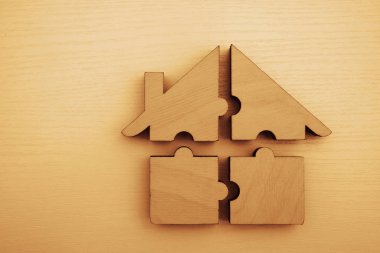  Dört parçadan yapılmış ahşap ev. Beyaz ahşap arka planda bulmacalar. Bir yapboz. Takım çalışması fikri. Yazı için boş kopyalama alanı.