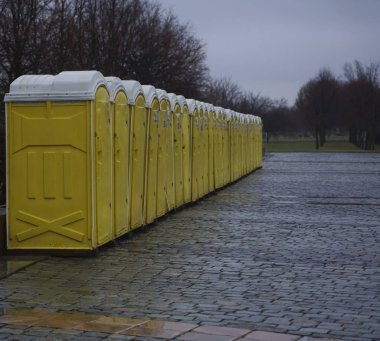 Yeşil ağaçlara karşı parktaki dolapların sarı kulübeleri. Moskova, Rusya. Yağmurlu günlerde parkta gezici tuvaletler.