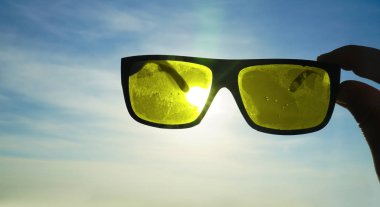 Gün batımında güneş, deniz ve gökyüzü manzarası. Güneş gözlükleriyle denizin üzerinde gün batımı.