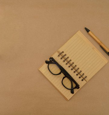 Açık defter, kalem ve gözlüklü üst görünüm masası 