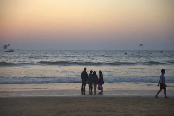 Silhouette of Happy family standing on the beach on the dawn time. Mother, father  and two grown, adults daughters  standing on beach at sunset. back, rear view.
