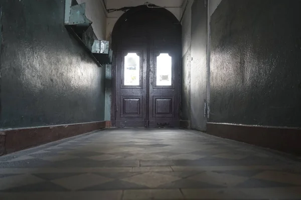 vintage aged  wooden doors in the interior, architecture. A large hall in a high entrance with white and green walls. open glass door at the end of  corridor illuminated by the light from the window.