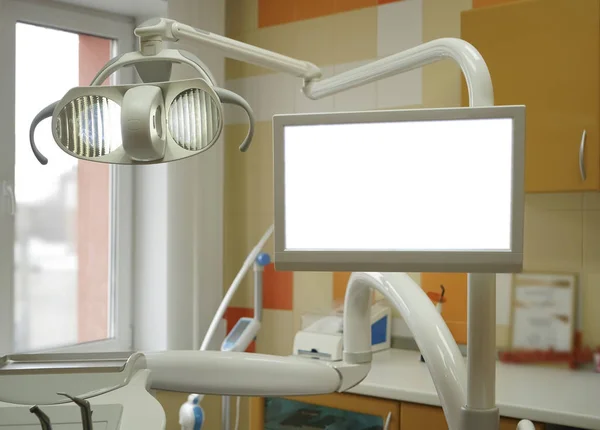 Dental clinic with modern interior design and big window. Dental chair, equipment, tools, computer and other accessories used by dentists. Cabinet in orange and white colors