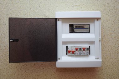 Gri duvarlı kır evi için elektrik sayacı ve devre kesicili beyaz plastik kalkan.