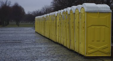 Yeşil ağaçlara karşı parktaki dolapların sarı kulübeleri. Moskova, Rusya. Yağmurlu günlerde parkta gezici tuvaletler.
