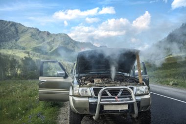 overheated car in the field, bright sunlight, steam under the ho