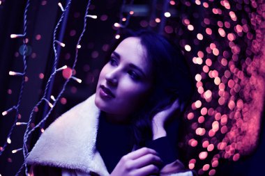 Güzel Asyalı kız şafak vakti şehir sokağına bakıyor. Bokeh ile arkaplan. 