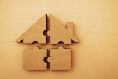  Dört parçadan yapılmış ahşap ev. Beyaz ahşap arka planda bulmacalar. Bir yapboz. Takım çalışması fikri. Yazı için boş kopyalama alanı.