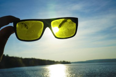 Gün batımında güneş, deniz ve gökyüzü manzarası. Güneş gözlükleriyle denizin üzerinde gün batımı.