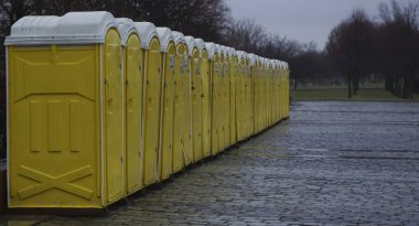 Yeşil ağaçlara karşı parktaki dolapların sarı kulübeleri. Moskova, Rusya. Yağmurlu günlerde parkta gezici tuvaletler.