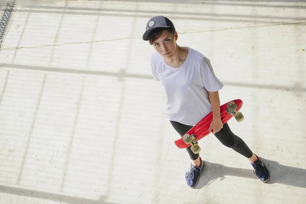 portrait of teen girl with long skate board standing  against gray wall. Outdoors, urban lifestyle. top view.