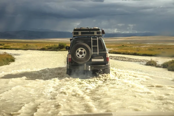 black four by four car crossing a river with splashing water, Travel concept for off-road adventure and fun in mountain Altai landscape.