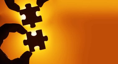 Gökyüzü arka planında yapboz parçaları olan eller.  