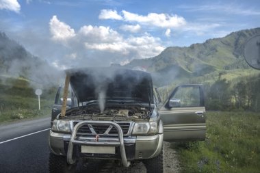 overheated car in the field, bright sunlight, steam under the ho
