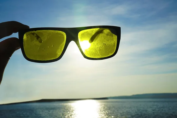 view of the sun, sea and sky through sunglasses at sunset. Sunset over the sea through sunglasses.