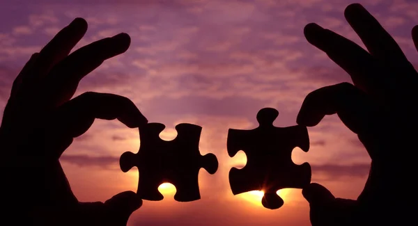 hands  with  puzzle pieces on sky background.