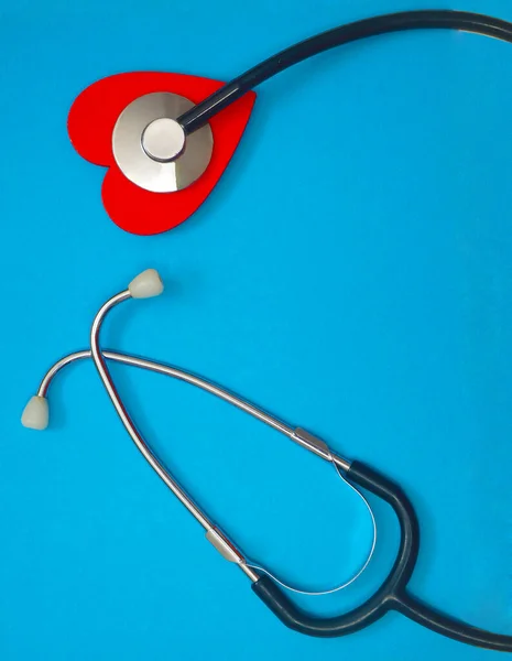 蓝纸背景上的红心听诊器保健概念 保健工作者 心脏保健 医疗护理 平面布局 顶视图 — 图库照片