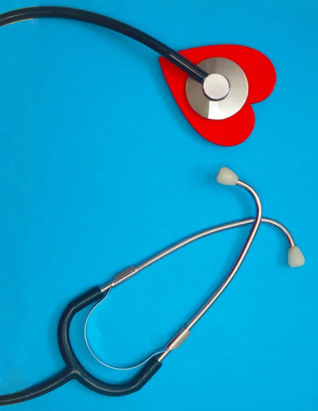 蓝纸背景上的红心听诊器保健概念 保健工作者 心脏保健 医疗护理 平面布局 顶视图 — 图库照片