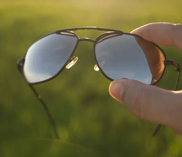 Male Hand Holding Sunglasses Fresh Green Grass Field Meadow Sunset — Stock Photo, Image