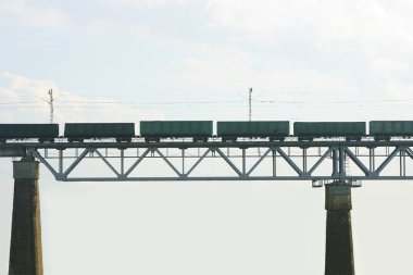 Tren demiryolu köprüsünden geçiyor. Yük treni nehrin karşısındaki demiryolu köprüsünde. Güzel güneşli yaz günü.