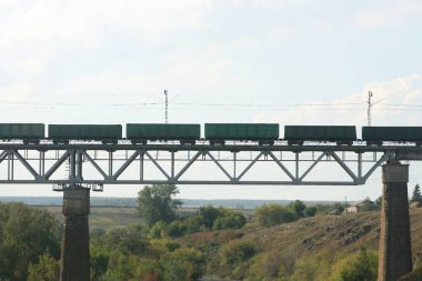 Tren demiryolu köprüsünden geçiyor. Yük treni nehrin karşısındaki demiryolu köprüsünde. Güzel güneşli yaz günü.
