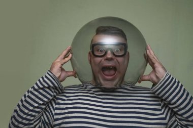 Erkek, dalış için gözlük takıyor ve yeşil duvar arka planında izole edilmiş akvaryumu yukarıda tutuyor.. 