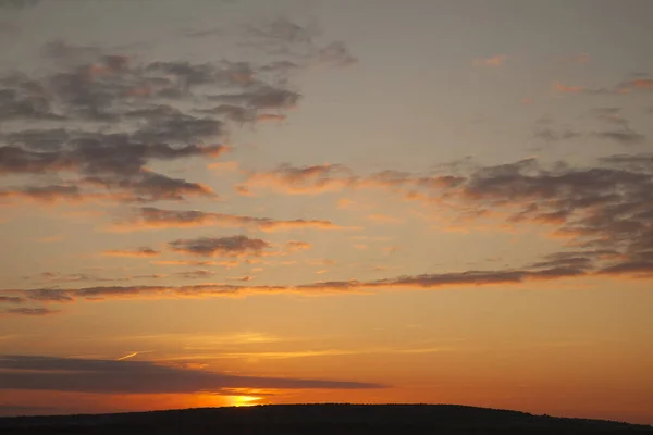 Bright big sun on the sky with clouds. Sun going down touching horizon line