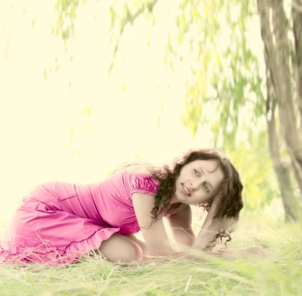 穿着紫罗兰色衣服的红头发年轻女人坐在绿草的草地上 春季季节 — 图库照片